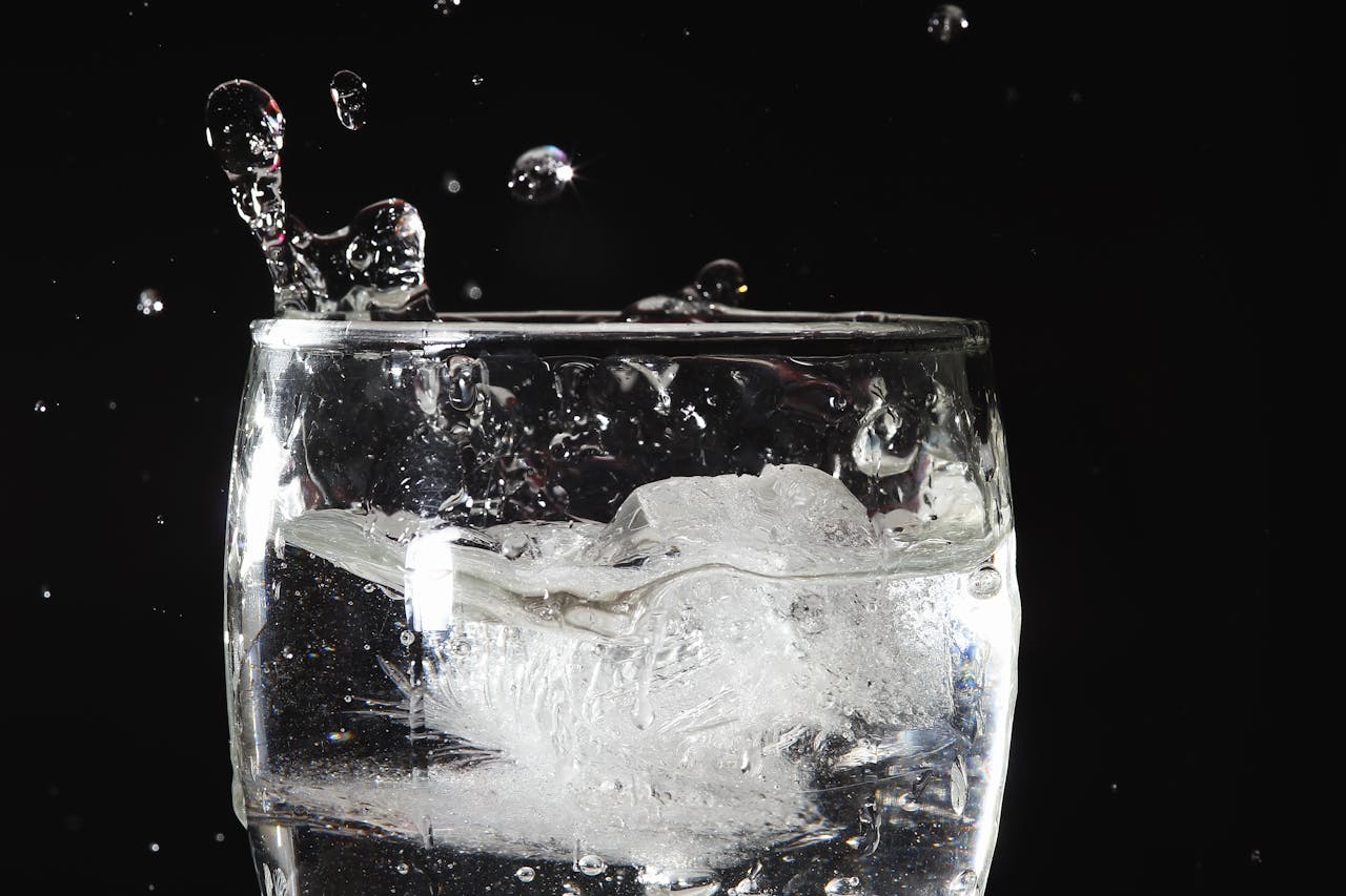 High-speed capture of ice impacting water in a glass, creating dynamic splash effects.